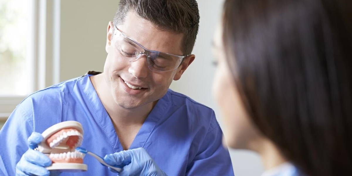 Dentist Demonstrating Correct Use Of Toothbrush To Female Client