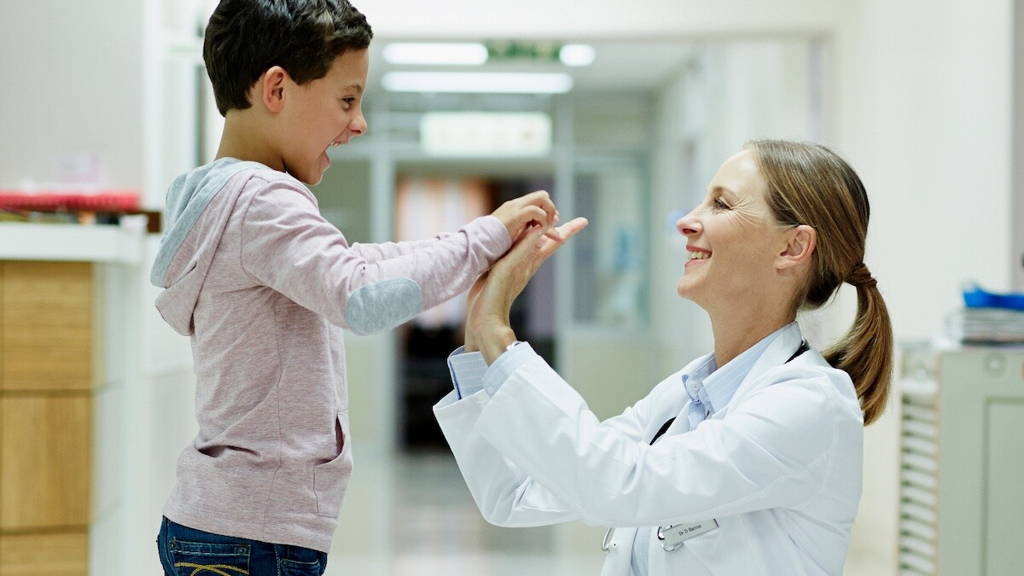 Vrouwelijke arts geeft een high-five aan kind in ziekenhuis