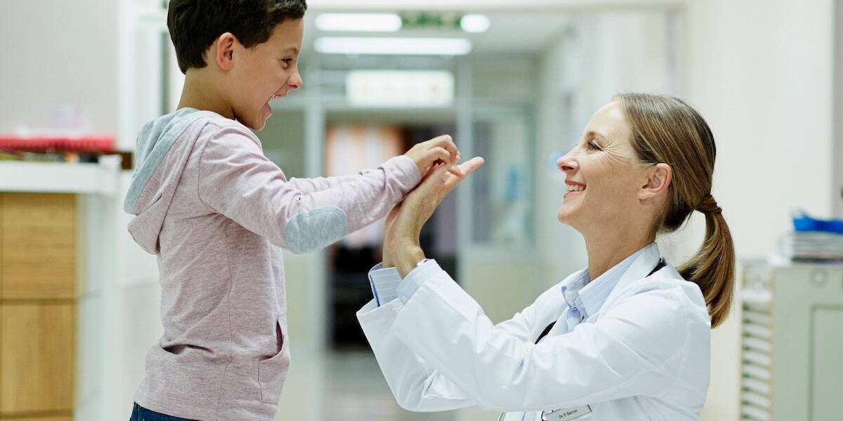 Vrouwelijke arts geeft een high-five aan kind in ziekenhuis