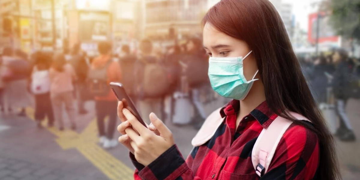 Asian Young woman using smart phone in the city wearing face mas