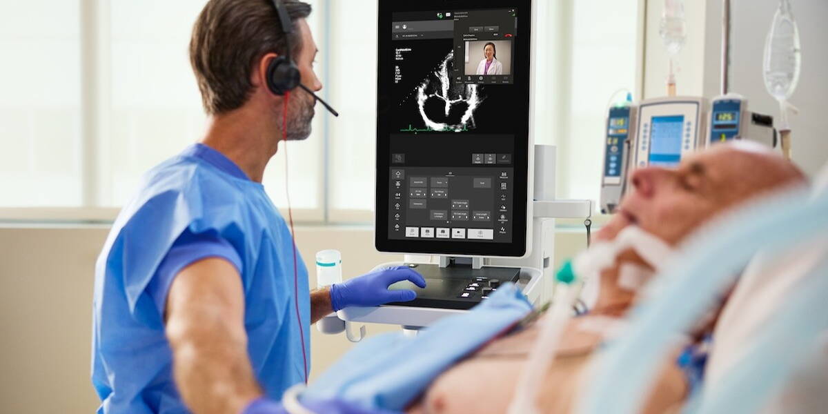 Mannelijke medische professional voert echografie-onderzoek uit bij een oudere man die aan de beademing ligt.