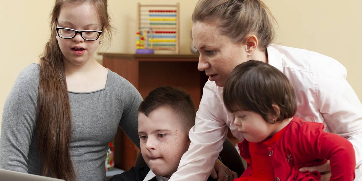 woman showing children with down syndrome something laptop