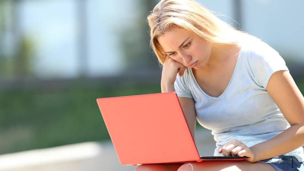 Frustrated student studying using laptop in a campus