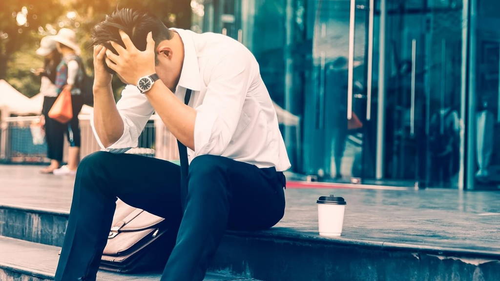 Workers man sitting headache in front of the company about his w
