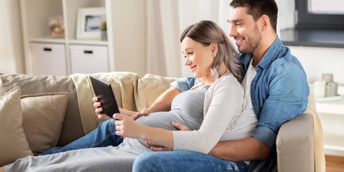 man and pregnant woman with tablet pc at home