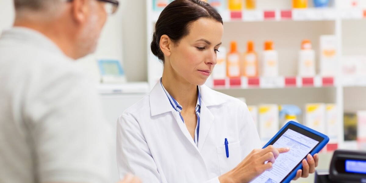 apothecary and customer with tablet pc at pharmacy