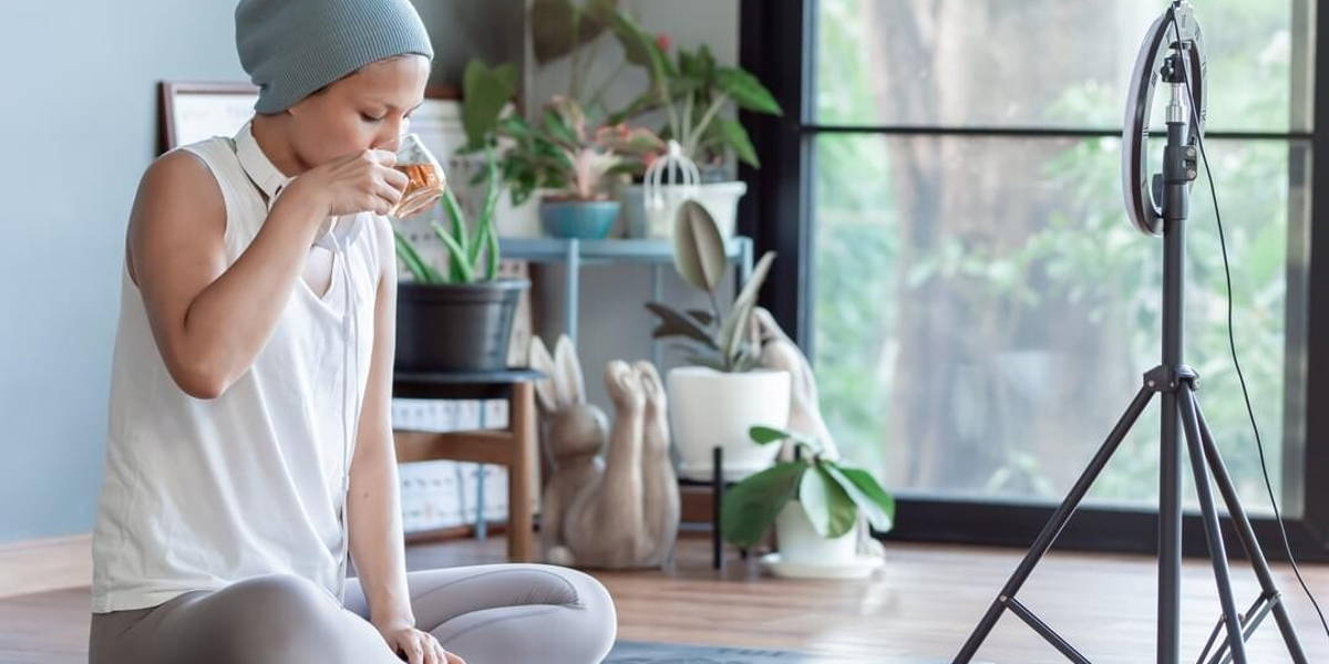 Cancer woman drinking tea while online streaming at home