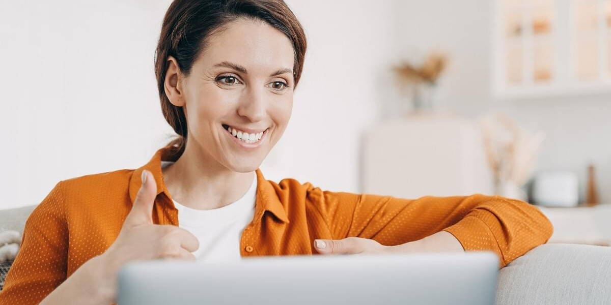 Young spanish woman is speaking online and showing thumb. Girl h