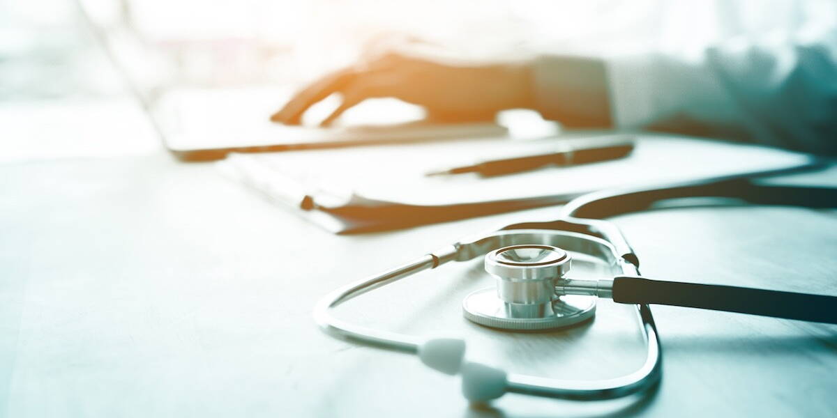 Doctor using laptop at desk in clinic working on computer at room office.