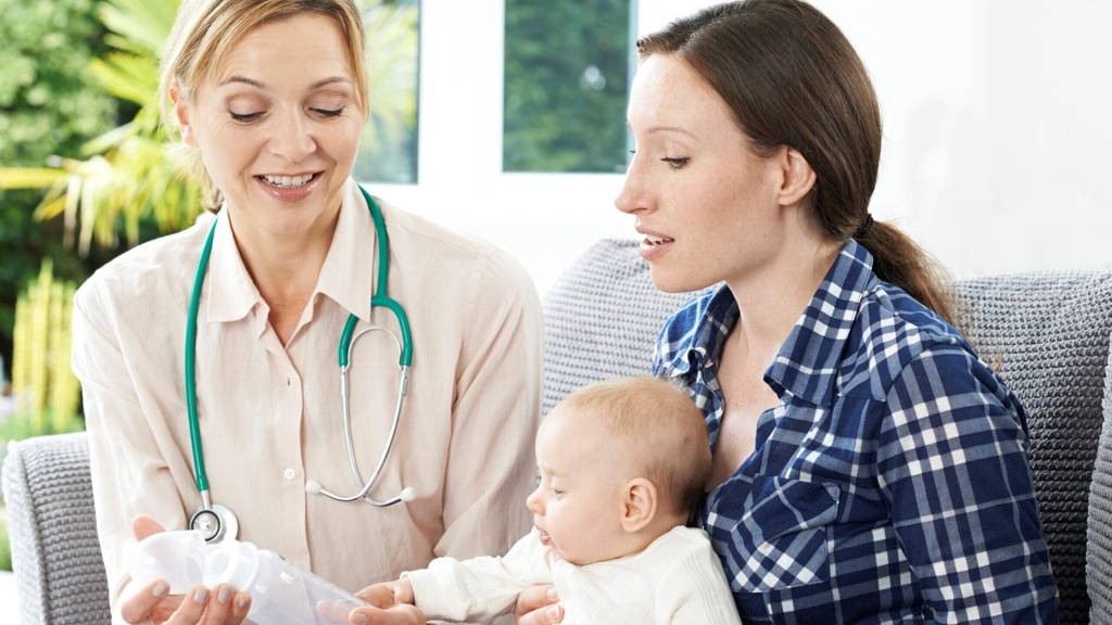 Health Visitor Giving Mother Advice On Feeding Baby With Bottle