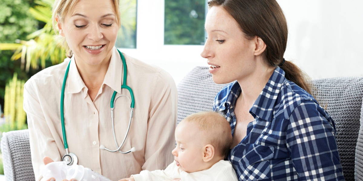 Health Visitor Giving Mother Advice On Feeding Baby With Bottle